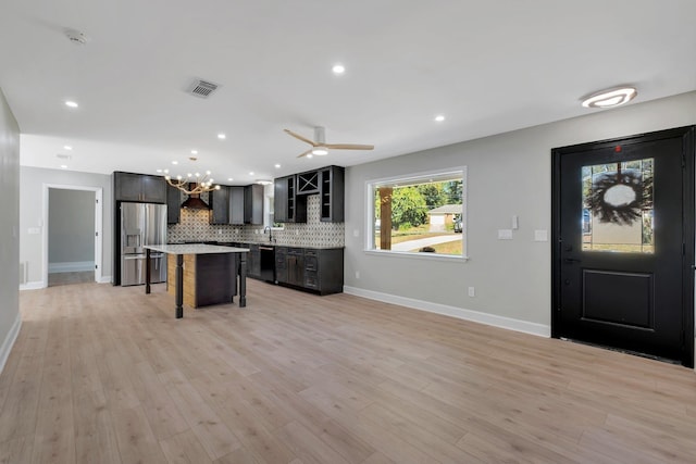 kitchen with backsplash, dishwasher, a center island, stainless steel refrigerator with ice dispenser, and a kitchen breakfast bar