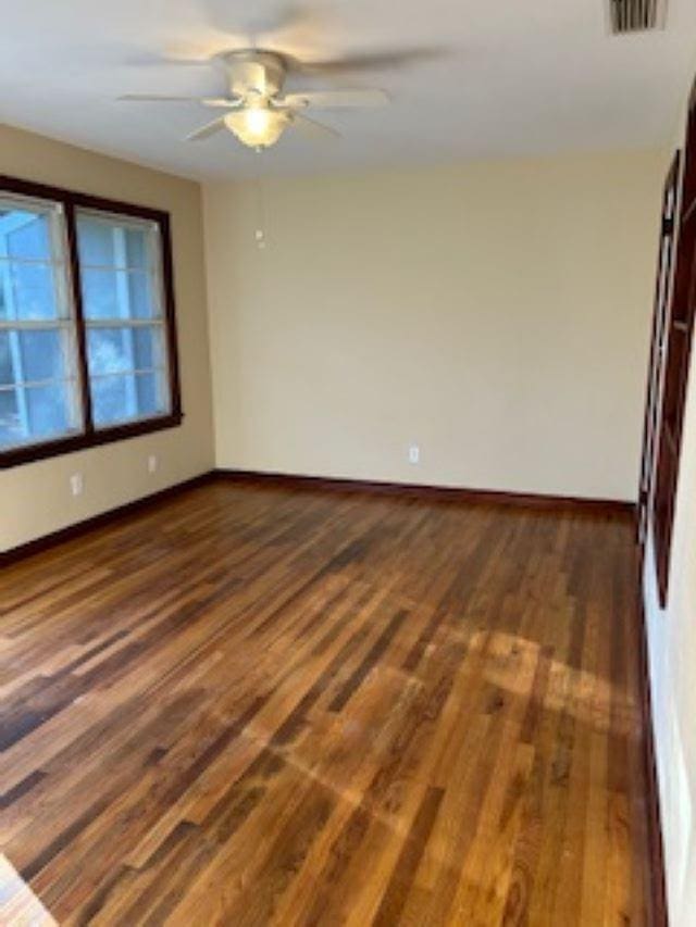 empty room with dark wood-type flooring and ceiling fan