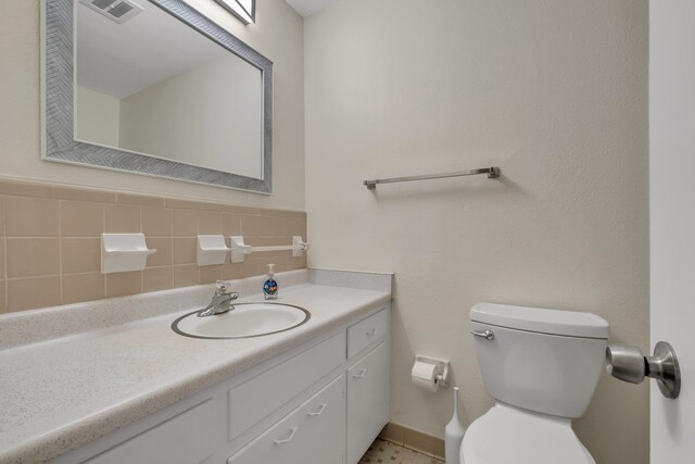 bathroom featuring vanity, tasteful backsplash, and toilet