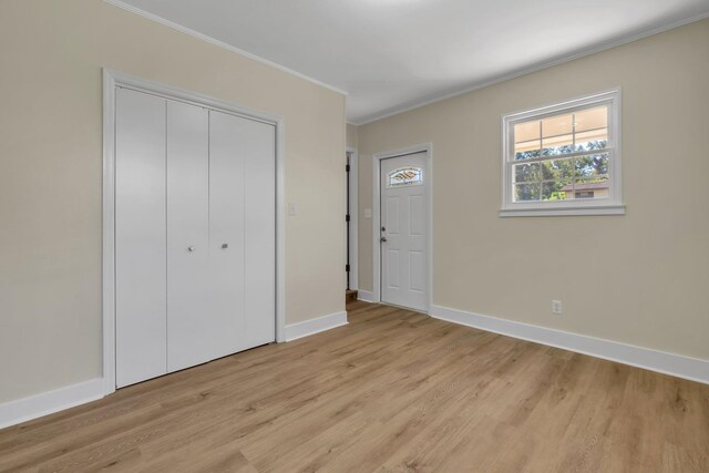 unfurnished bedroom featuring a closet, ornamental molding, and light hardwood / wood-style flooring