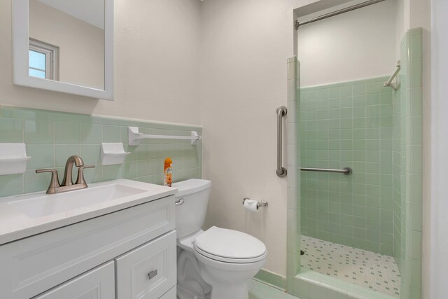 bathroom featuring tile walls, vanity, toilet, and a tile shower