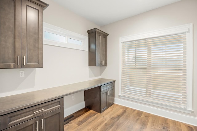 kitchen with a healthy amount of sunlight, light hardwood / wood-style flooring, and built in desk