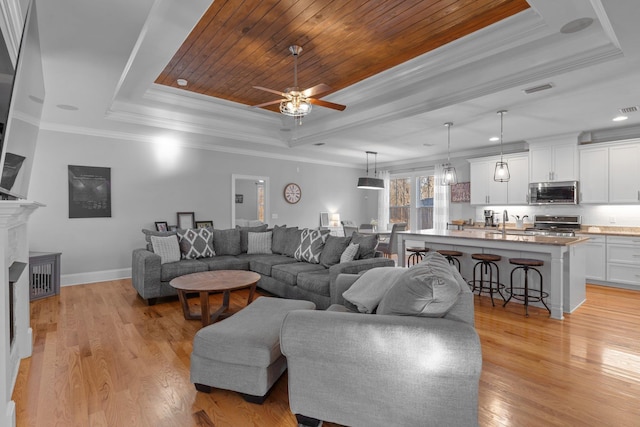 living room featuring a tray ceiling, ornamental molding, light hardwood / wood-style floors, and wooden ceiling