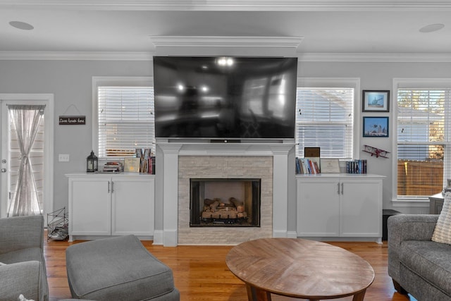 living room with ornamental molding, a fireplace, and light wood-type flooring