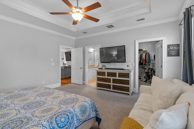 carpeted bedroom with connected bathroom, a spacious closet, ornamental molding, a raised ceiling, and a closet