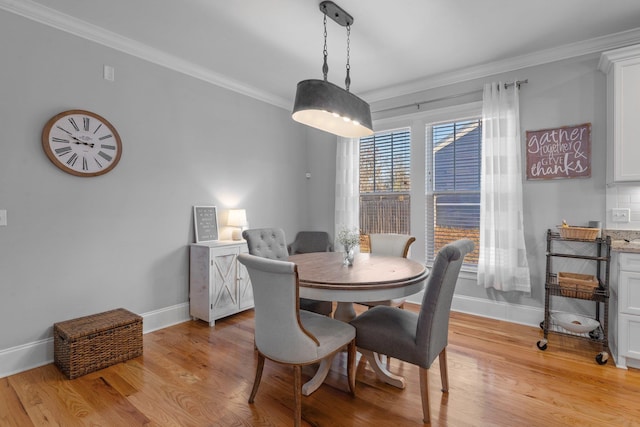 dining area with crown molding and light hardwood / wood-style flooring