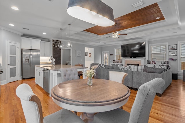 dining space featuring ornamental molding, light hardwood / wood-style flooring, and a tray ceiling