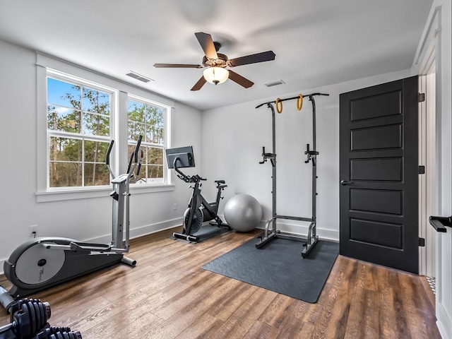 workout area with a ceiling fan, baseboards, visible vents, and wood finished floors