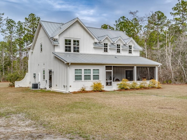 back of property featuring a yard, board and batten siding, and a sunroom