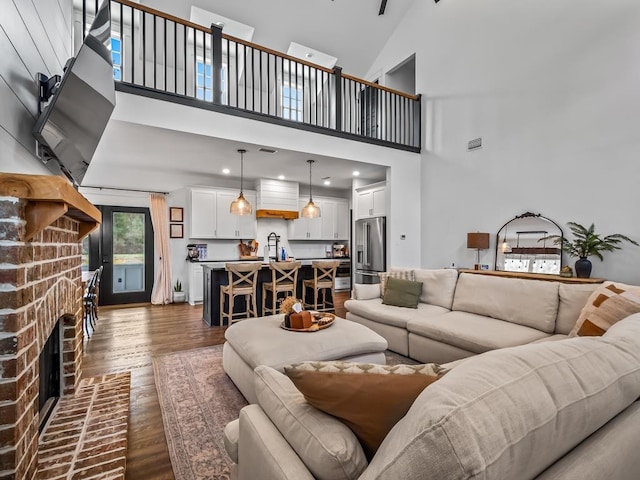 living area featuring visible vents, a fireplace, dark wood finished floors, and a towering ceiling