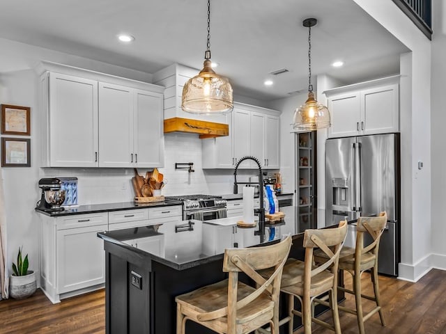 kitchen with backsplash, dark countertops, appliances with stainless steel finishes, dark wood-style floors, and white cabinetry