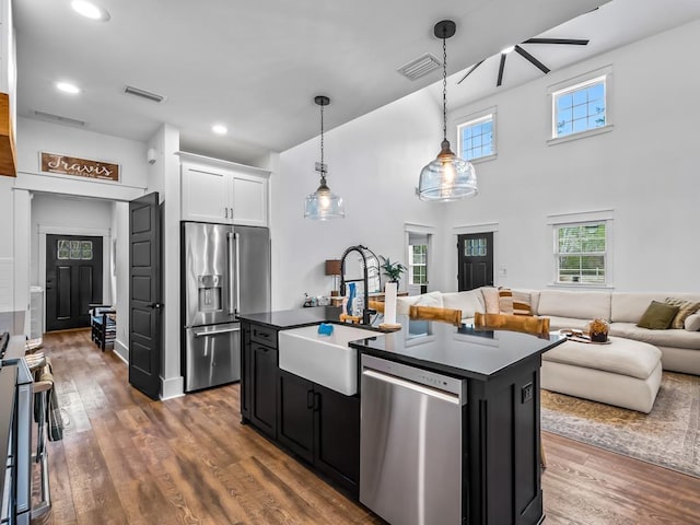 kitchen featuring dark countertops, a sink, open floor plan, dark cabinets, and stainless steel appliances