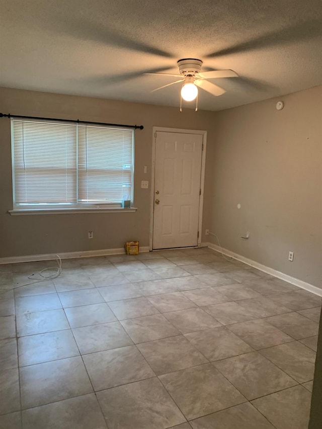 foyer featuring ceiling fan, light tile patterned flooring, and a textured ceiling