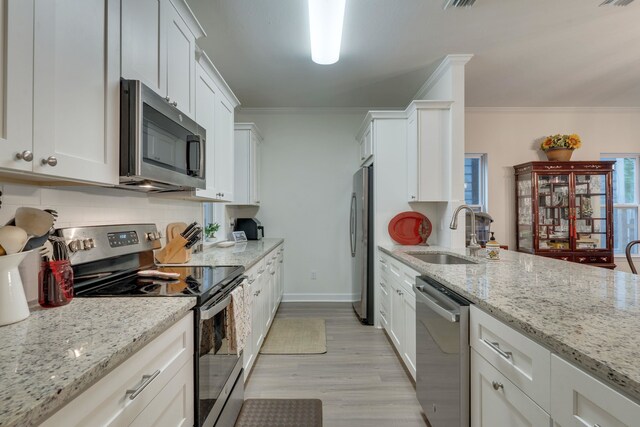 624 W 7th Ave Unit 1And 2, Tallahassee, FL 32303 - kitchen with appliances with stainless steel finishes, crown molding, white cabinetry, light wood-style floors, and light stone countertops
