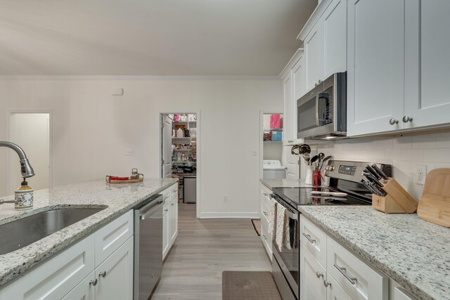 624 W 7th Ave Unit 1And 2, Tallahassee, FL 32303 - kitchen with appliances with stainless steel finishes, ornamental molding, light wood finished floors, decorative backsplash, and white cabinets