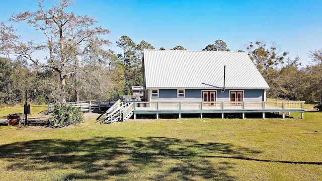 rear view of property featuring a yard, metal roof, and a wooden deck