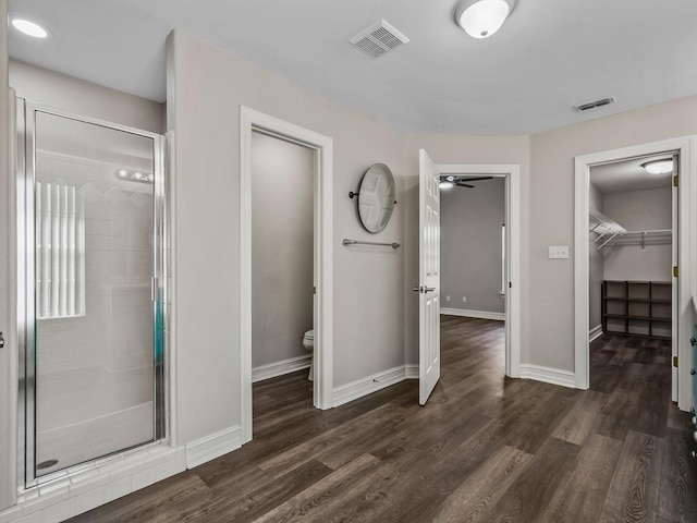 full bathroom featuring toilet, wood finished floors, visible vents, and a shower stall