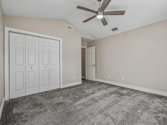 unfurnished bedroom featuring lofted ceiling, visible vents, dark carpet, and a closet