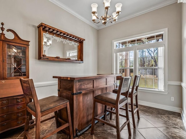 bar featuring crown molding, a dry bar, a chandelier, dark tile patterned flooring, and baseboards