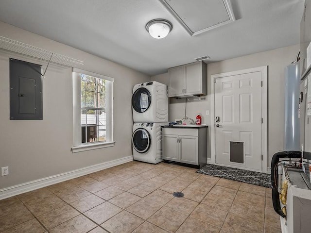 laundry area featuring stacked washer and clothes dryer, cabinet space, visible vents, light tile patterned flooring, and electric panel