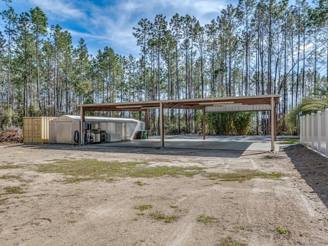 view of car parking featuring a carport, driveway, and a storage shed