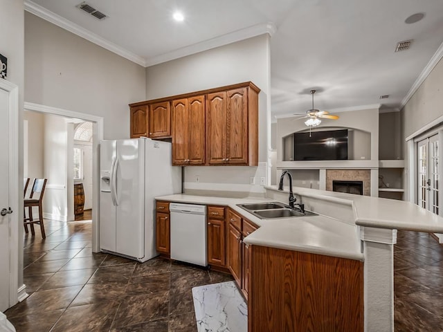 kitchen with a peninsula, white appliances, a sink, light countertops, and brown cabinets