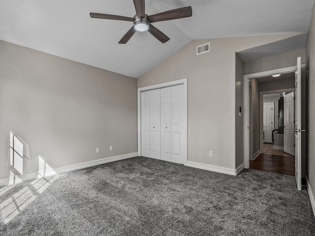 unfurnished bedroom with visible vents, baseboards, vaulted ceiling, a closet, and dark carpet