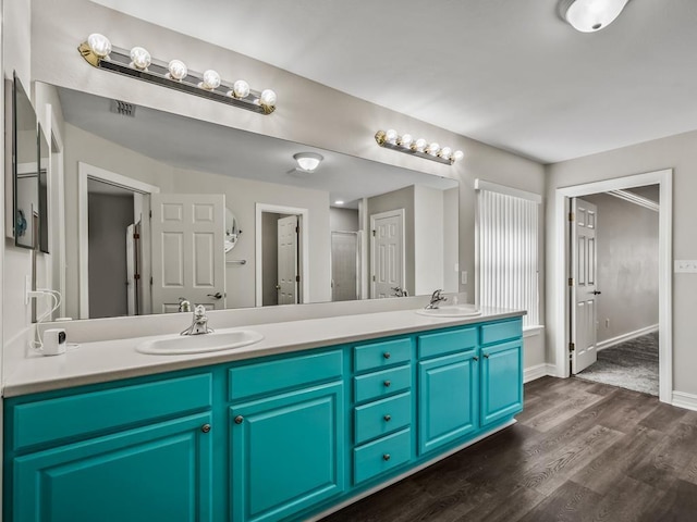 bathroom featuring wood finished floors, a sink, baseboards, and double vanity