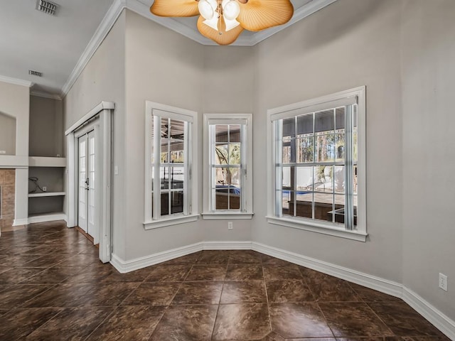 empty room with visible vents, crown molding, baseboards, and ceiling fan