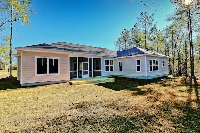 rear view of house featuring a lawn and a sunroom