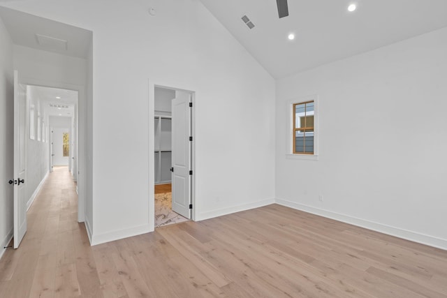 unfurnished bedroom featuring ceiling fan, a spacious closet, high vaulted ceiling, and light hardwood / wood-style flooring