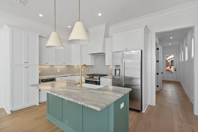 kitchen featuring decorative light fixtures, white cabinets, custom exhaust hood, stainless steel appliances, and a center island with sink