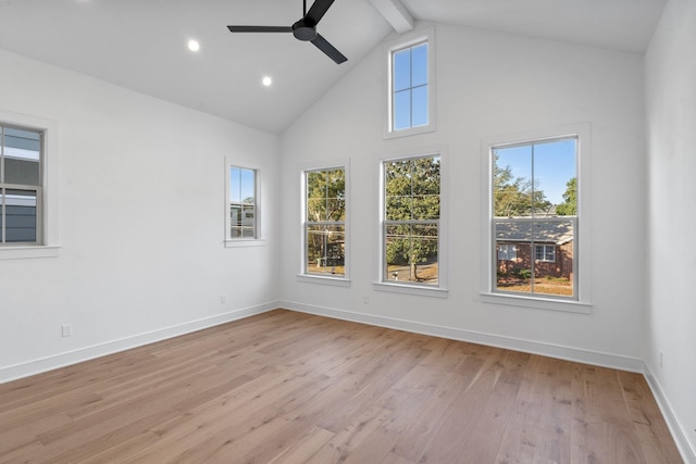 empty room with plenty of natural light, high vaulted ceiling, and light wood-type flooring