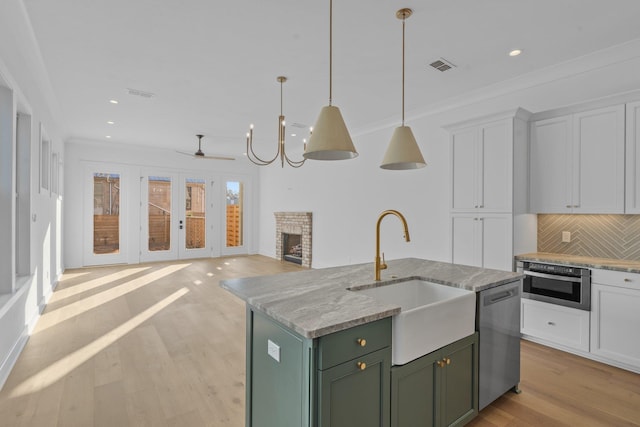 kitchen featuring sink, stainless steel appliances, white cabinets, and a center island with sink