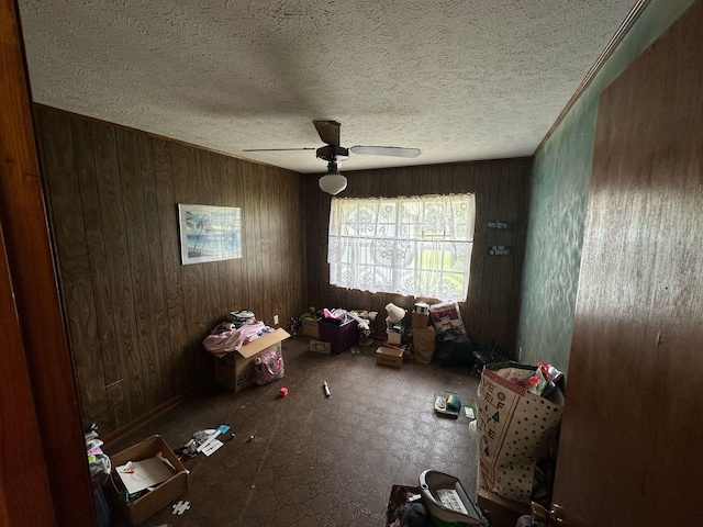 spare room featuring wood walls, a textured ceiling, and a ceiling fan