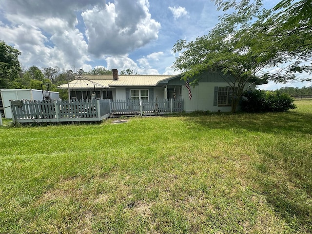 back of house featuring metal roof, a deck, a yard, and a chimney