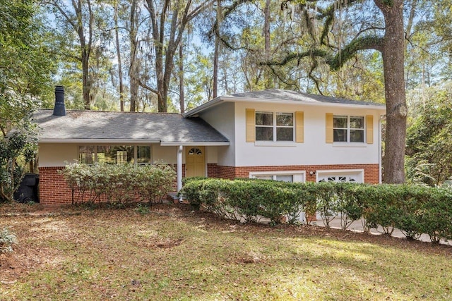 tri-level home featuring a garage, brick siding, a chimney, a front lawn, and stucco siding