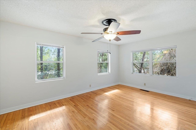 spare room with visible vents, a textured ceiling, light wood-style flooring, and baseboards