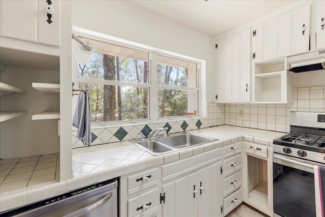 kitchen with open shelves, appliances with stainless steel finishes, a sink, and white cabinetry