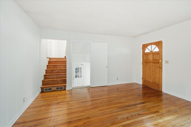 spare room featuring stairway, a textured ceiling, and wood finished floors