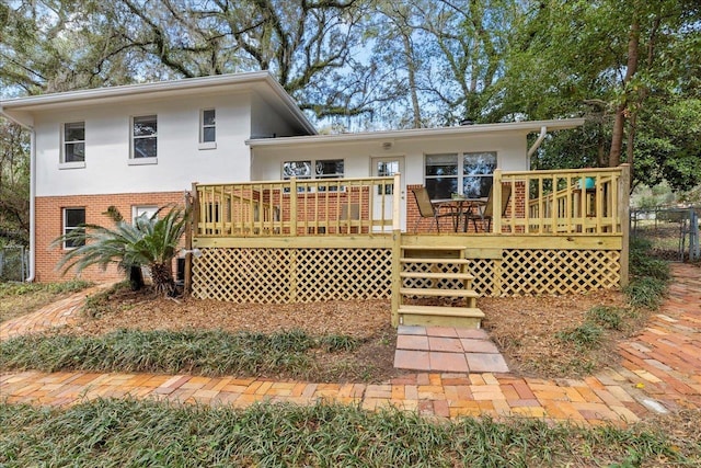 back of property featuring stucco siding, a deck, and brick siding