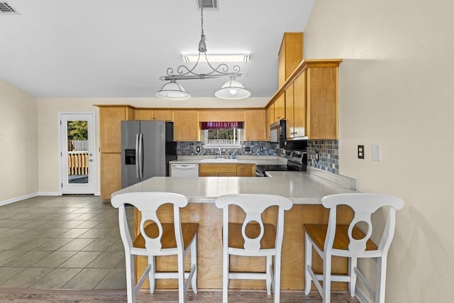 kitchen with sink, appliances with stainless steel finishes, tasteful backsplash, decorative light fixtures, and kitchen peninsula