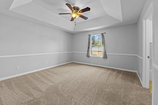 carpeted empty room with ceiling fan and a tray ceiling