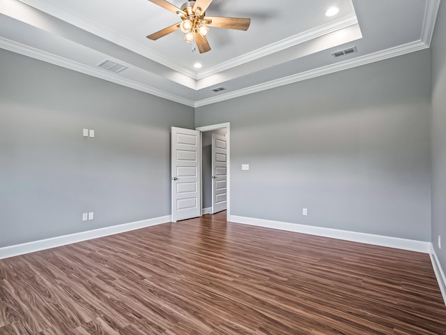 unfurnished room with ceiling fan, crown molding, a raised ceiling, and dark hardwood / wood-style flooring