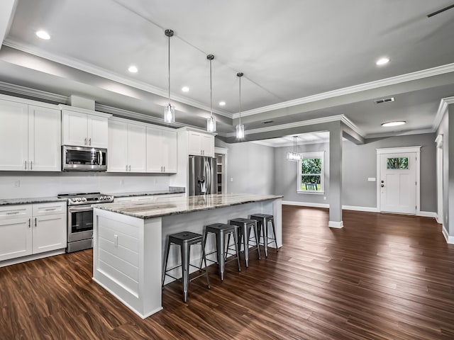 kitchen with white cabinets, stainless steel appliances, dark wood-type flooring, and a kitchen island