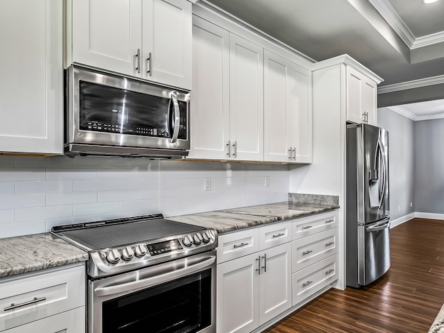 kitchen with dark wood-type flooring, crown molding, light stone countertops, white cabinetry, and appliances with stainless steel finishes