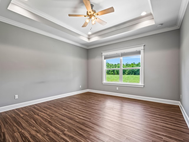 unfurnished room featuring ceiling fan, a tray ceiling, dark hardwood / wood-style floors, and crown molding