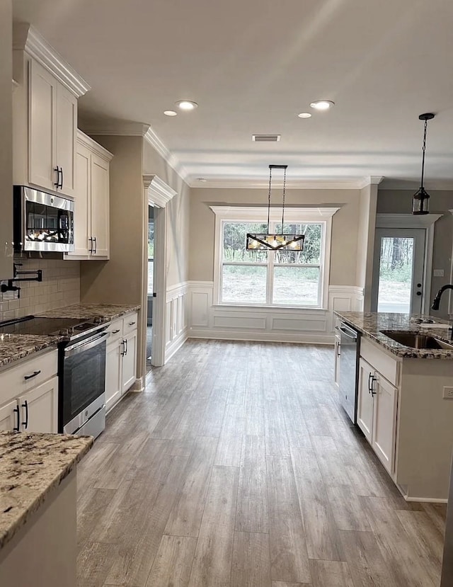 kitchen featuring light wood finished floors, plenty of natural light, appliances with stainless steel finishes, and a sink