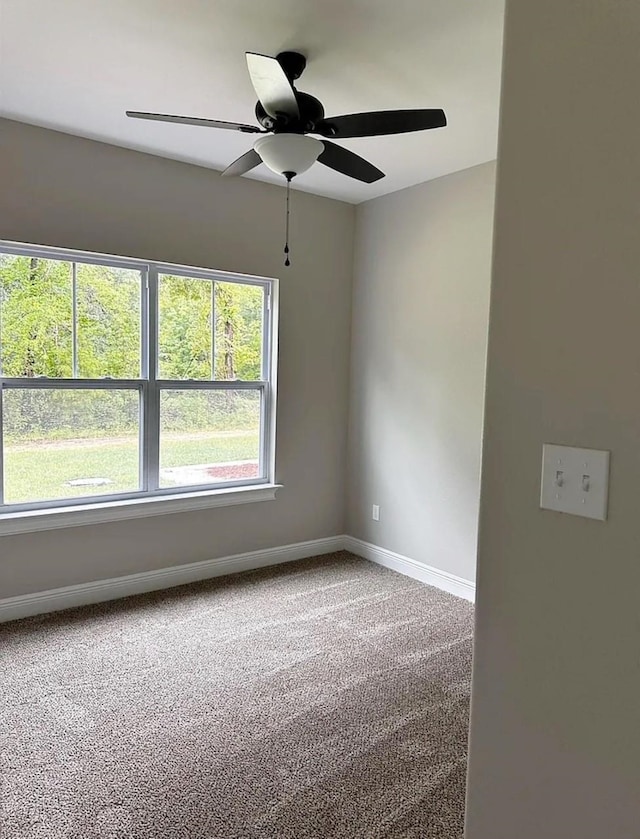 carpeted empty room with a ceiling fan and baseboards
