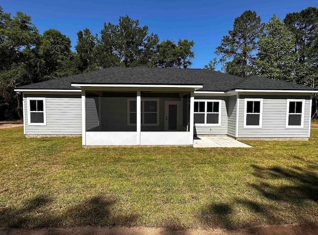 rear view of property with a patio, a yard, a sunroom, and roof with shingles
